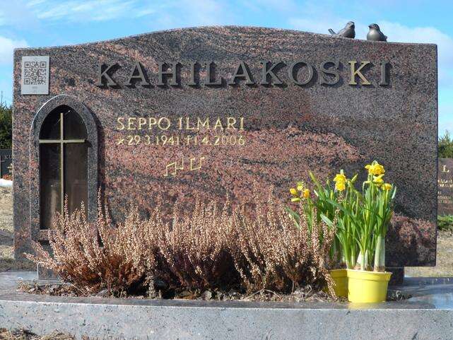 Muistolaatta, jossa on QR-koodi ja kukkia muistomerkillä